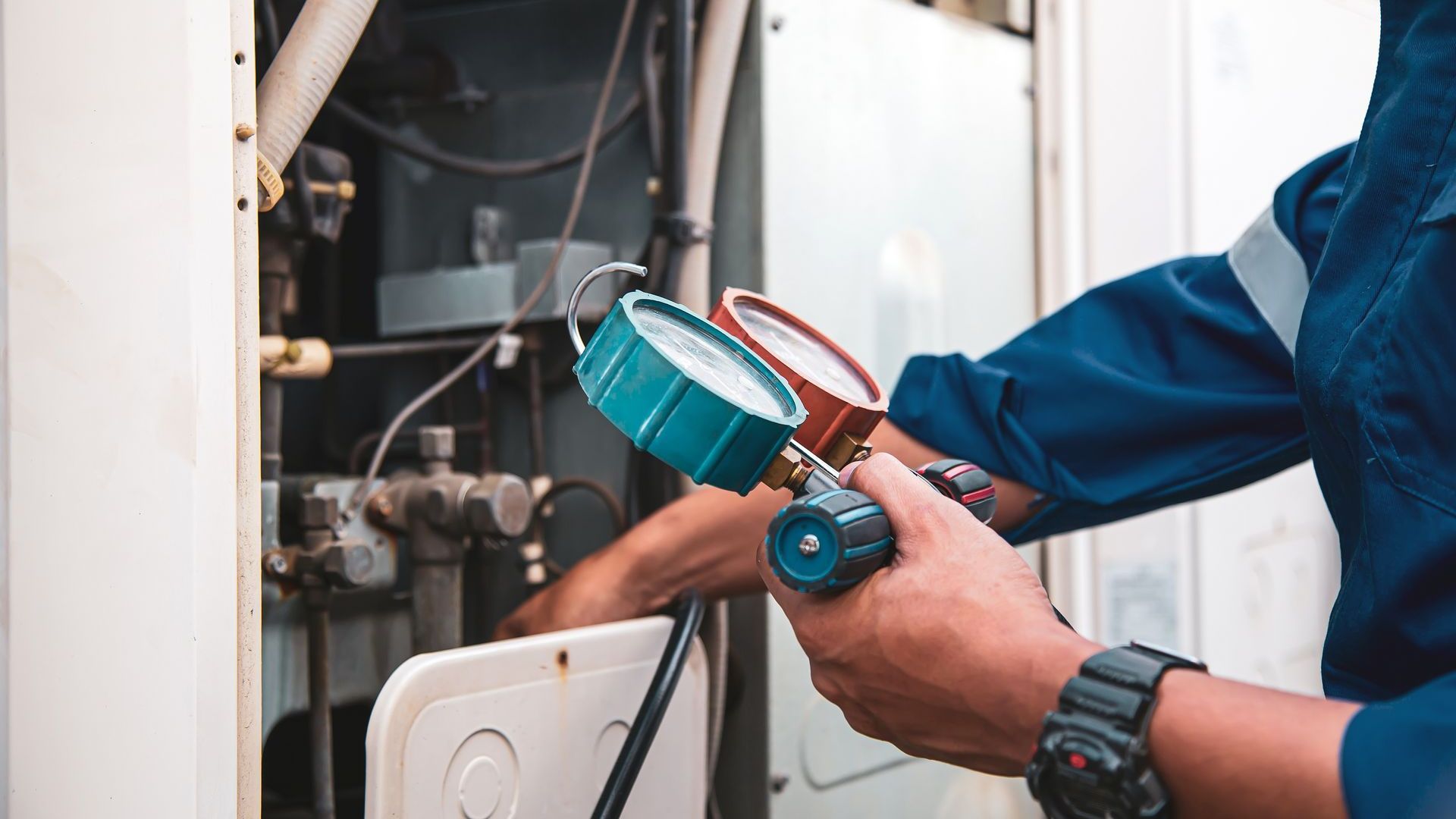 A man is holding a pressure gauge while working on a machine.