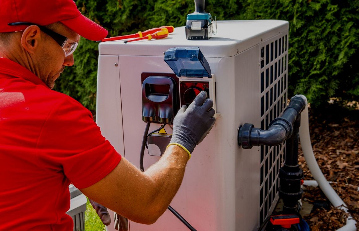 A man in a red shirt is working on a pool heater.