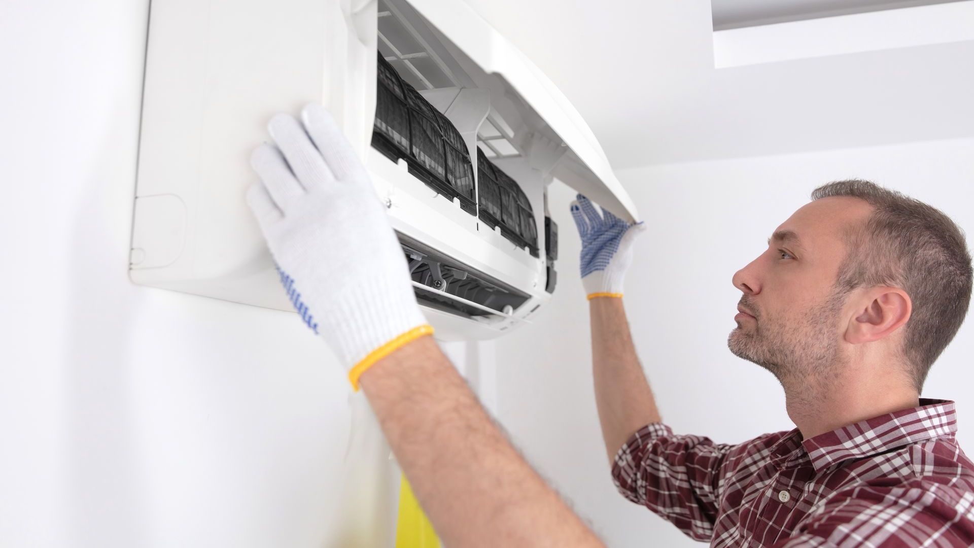 A man is cleaning the filter of an air conditioner.