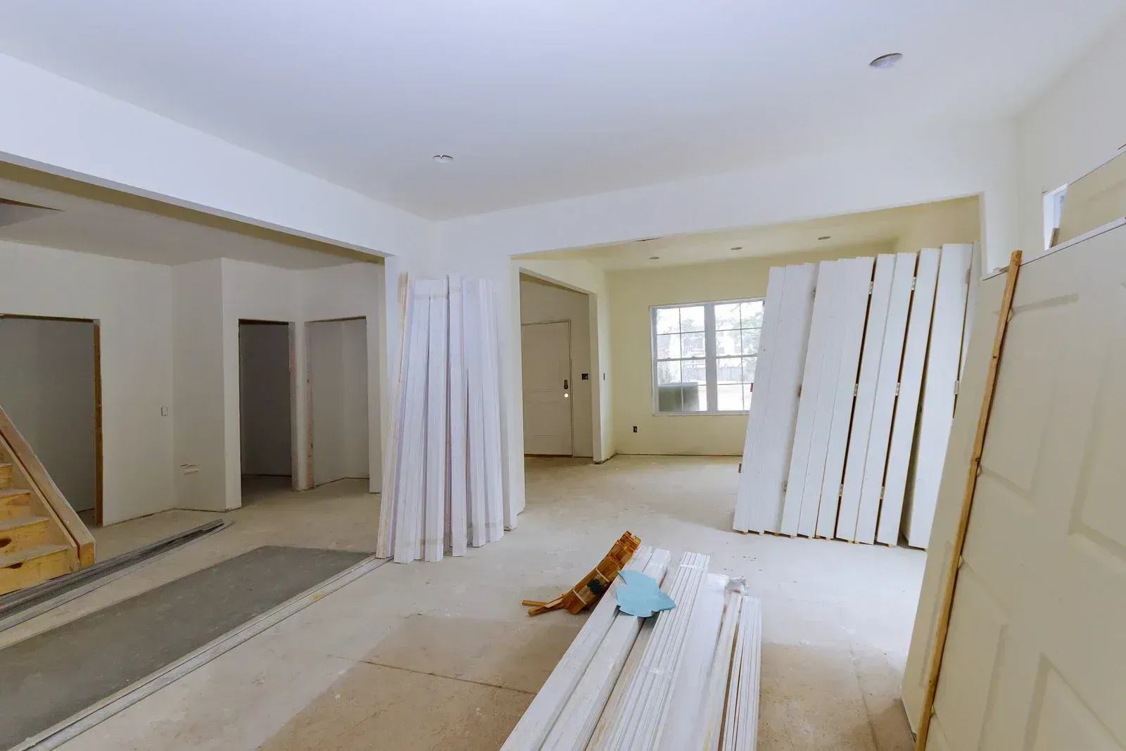 Interior of a house under construction, with stacked white building materials on light-colored floor.