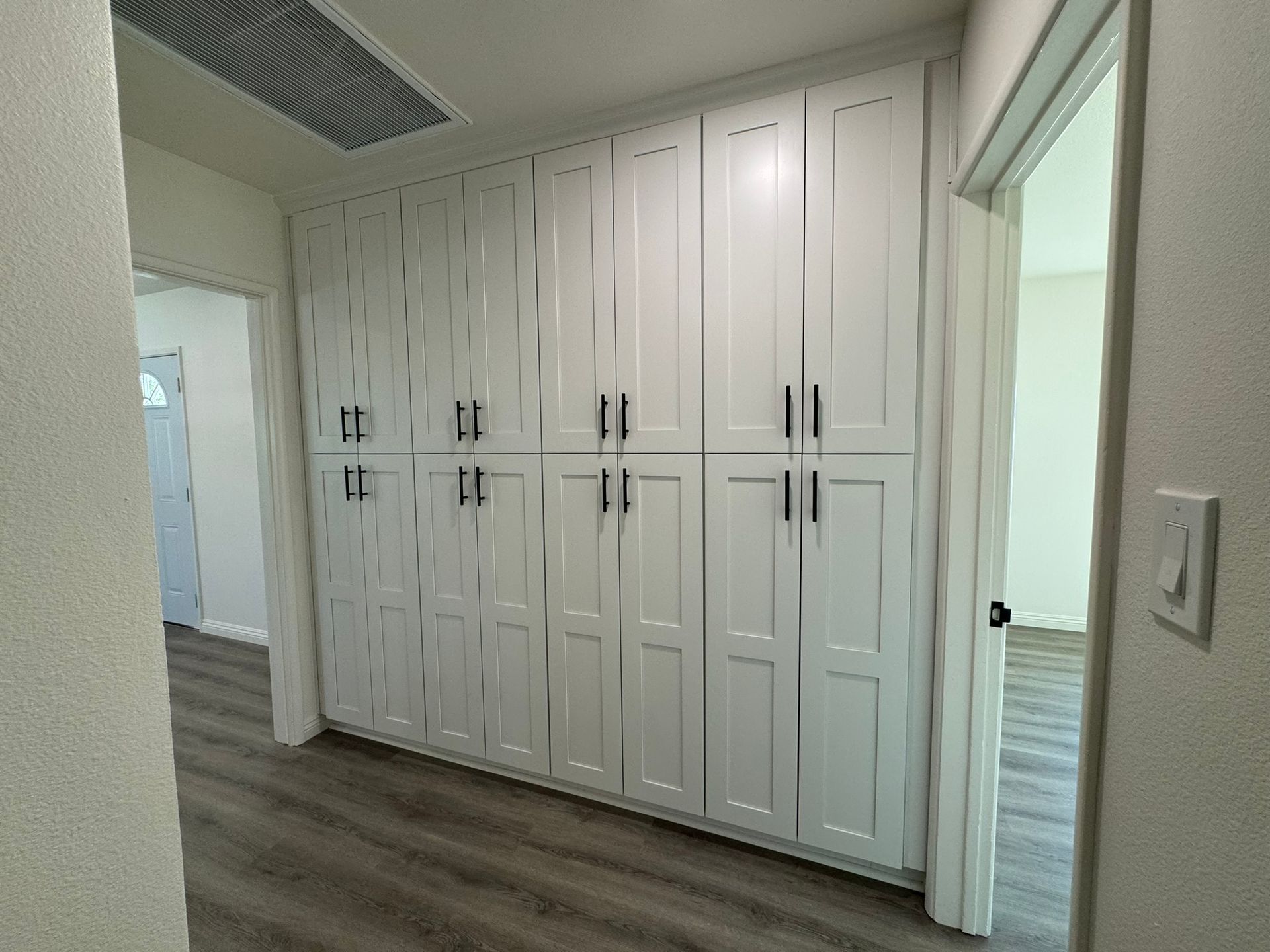 A hallway with a lot of white cabinets on the wall.