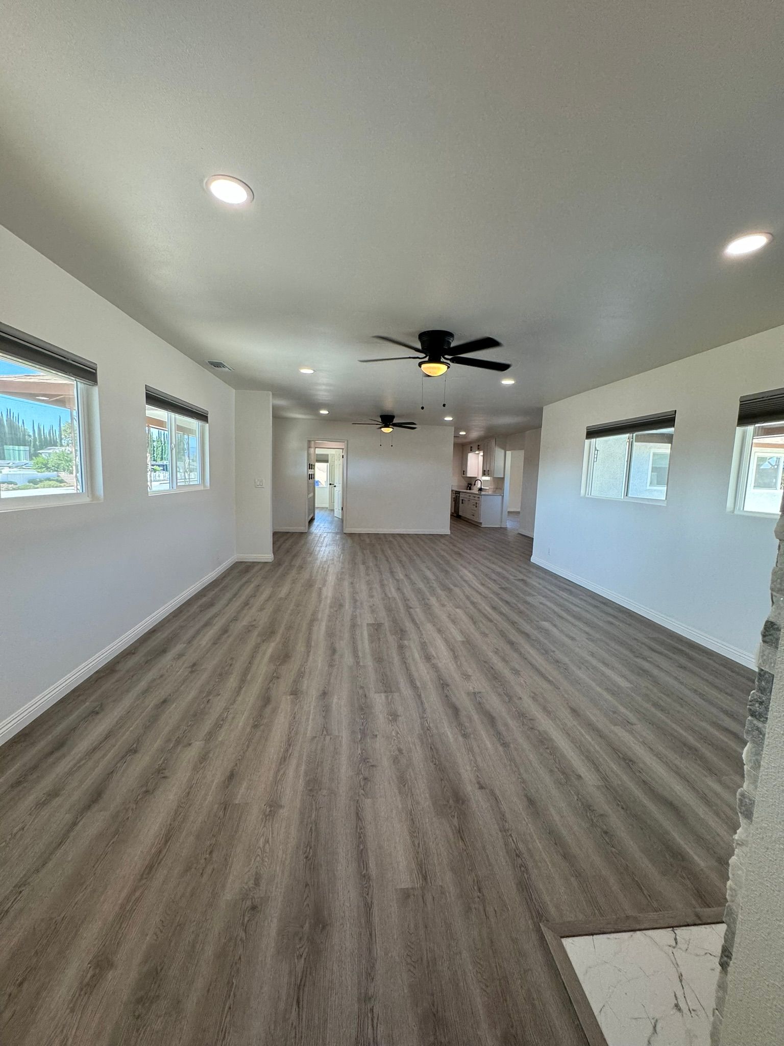 An empty living room with a lot of windows and curtains.