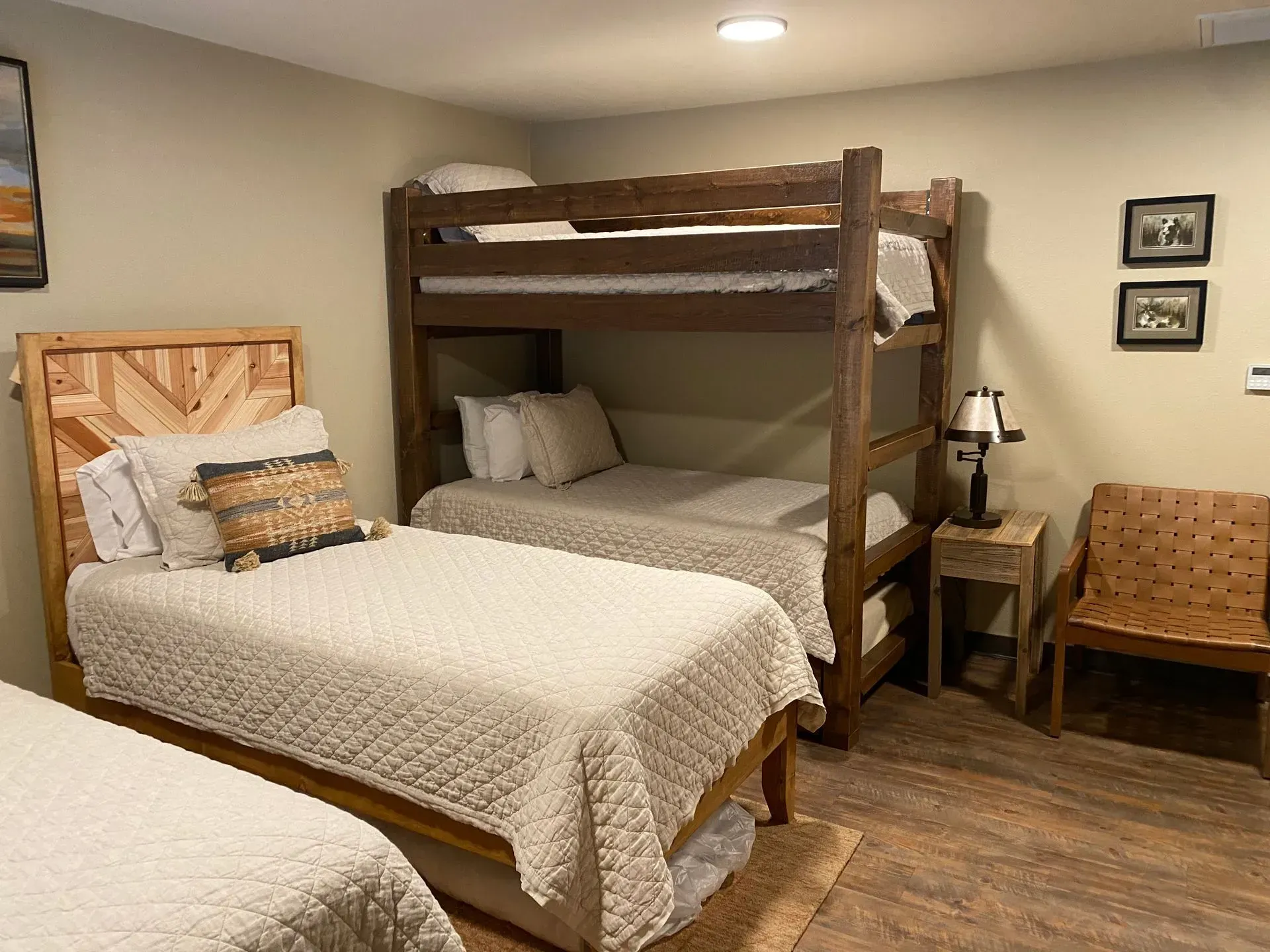 A bedroom with two twin beds and a bunk bed. The walls are neutral.