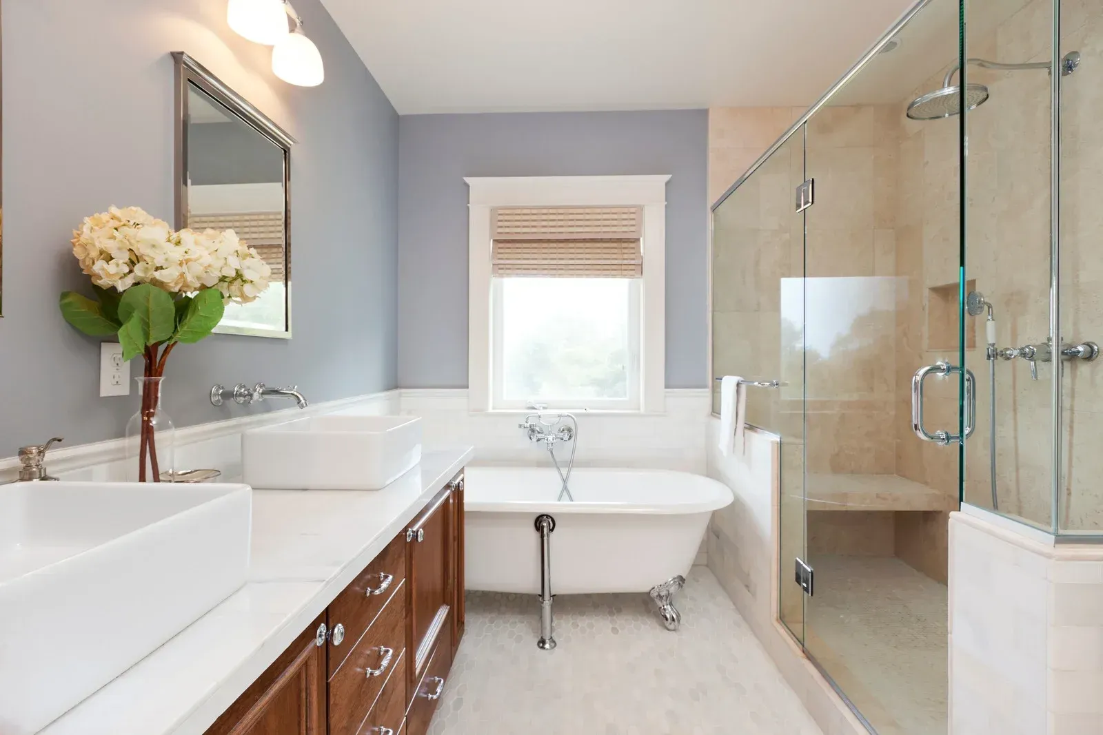 A bathroom with two sinks , a tub , a shower and a window.