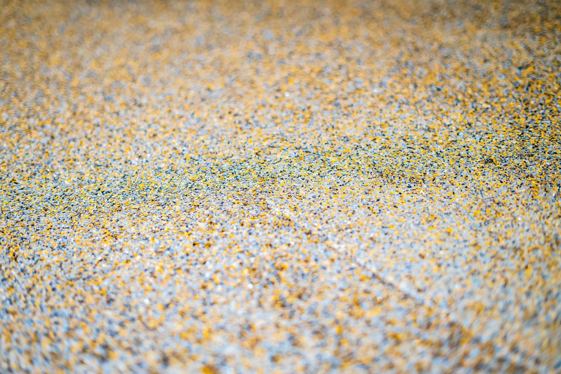 Close-up of a surface covered in tiny, tan and yellow granules, with a slight green line.