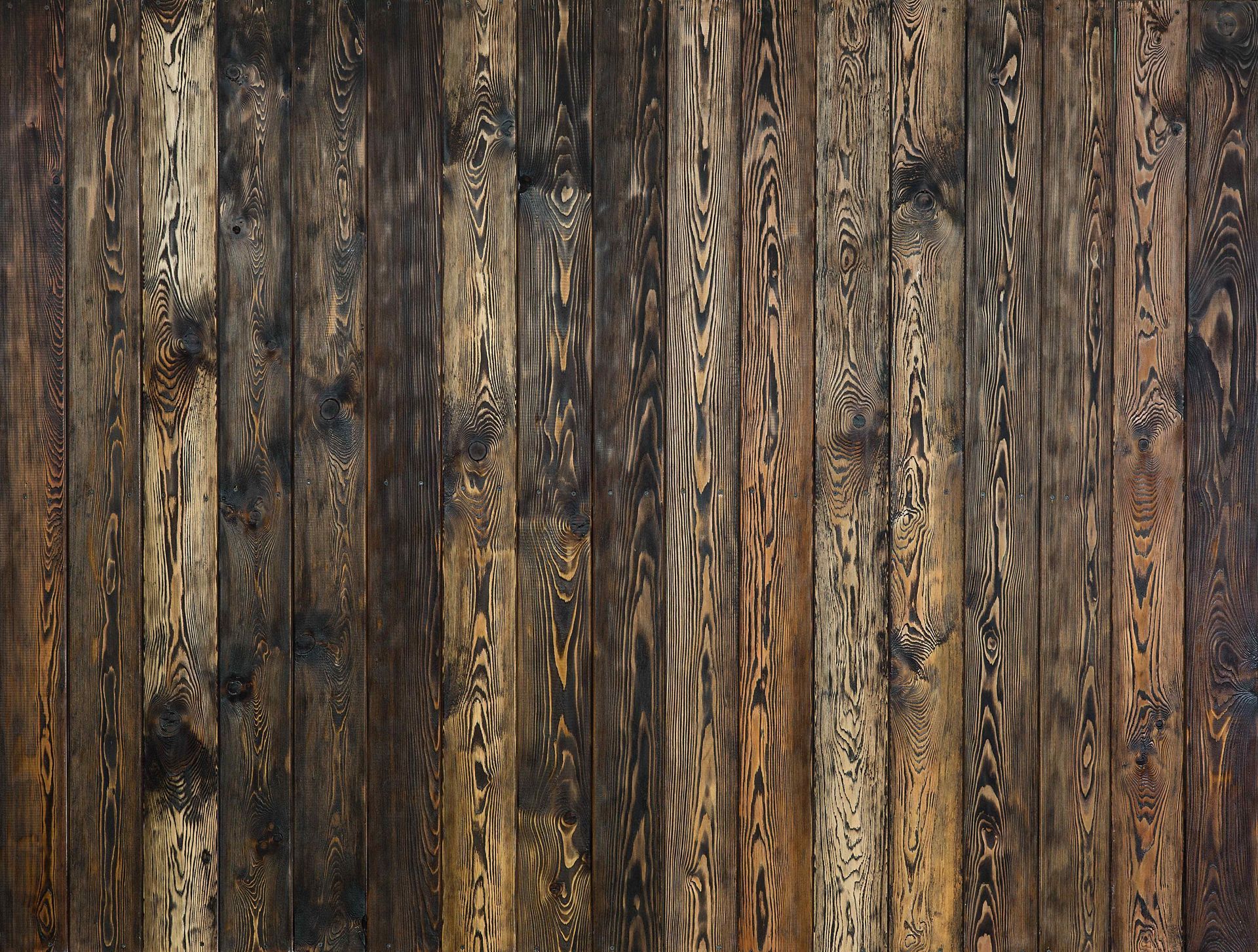 Dark wood plank wall with vertical, textured grain.