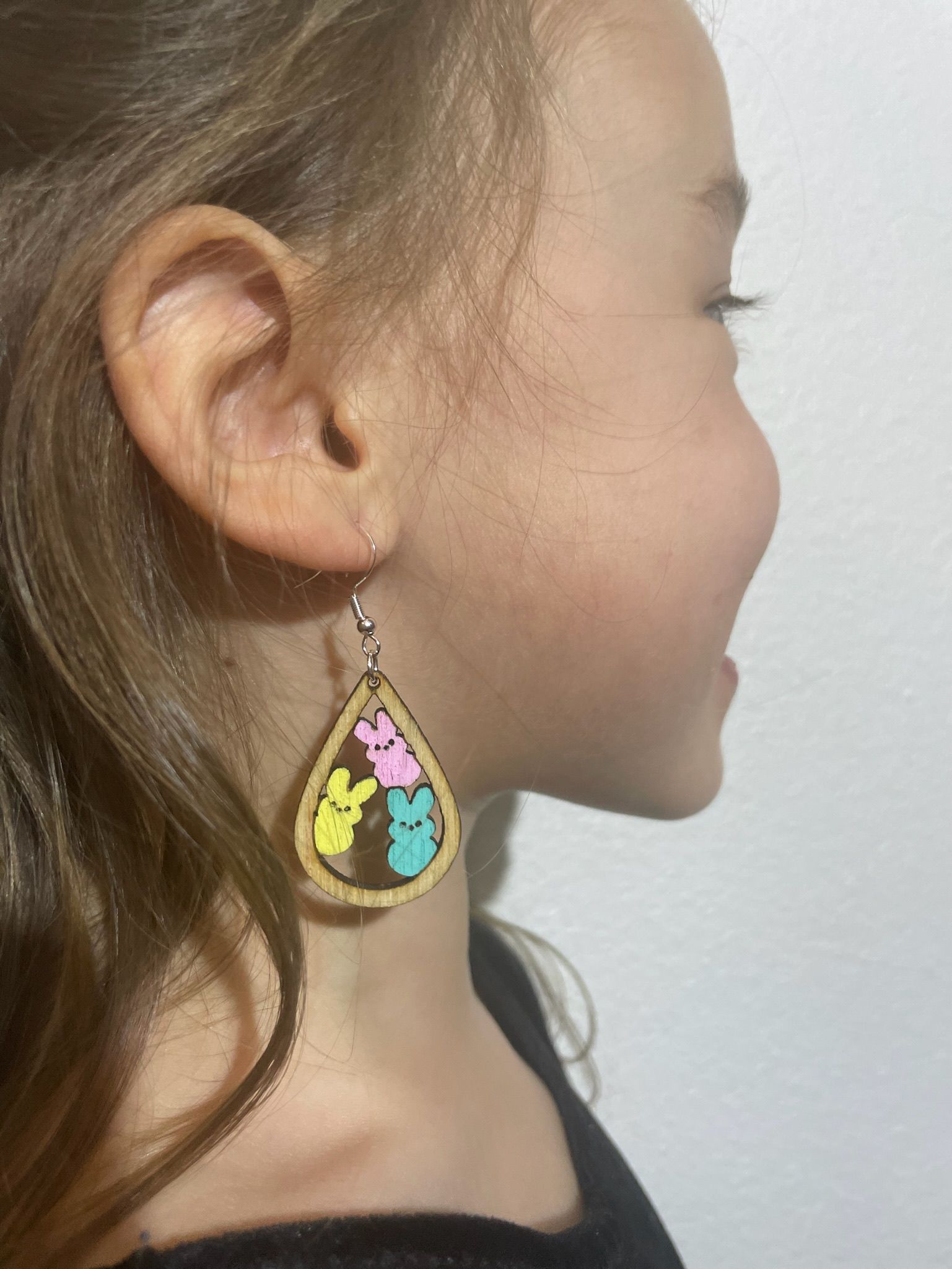 A little girl wearing a pair of bunny earrings.