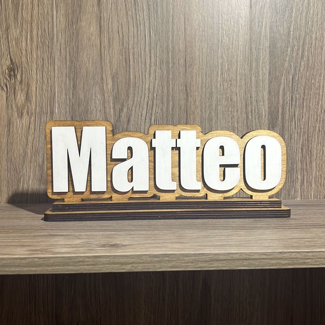 A wooden sign with the name matteo on it is sitting on a wooden shelf.