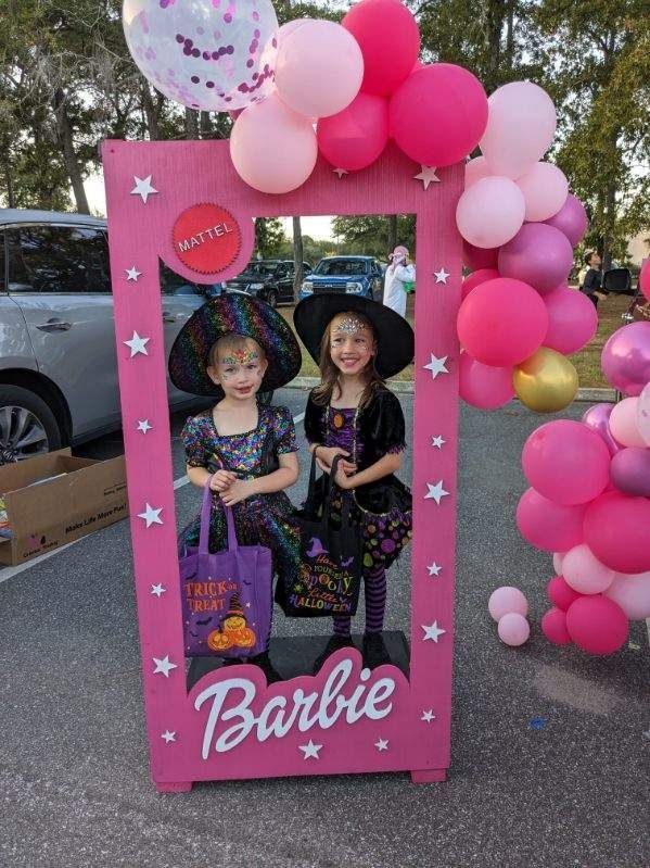 Two little girls are posing for a picture in a barbie frame.