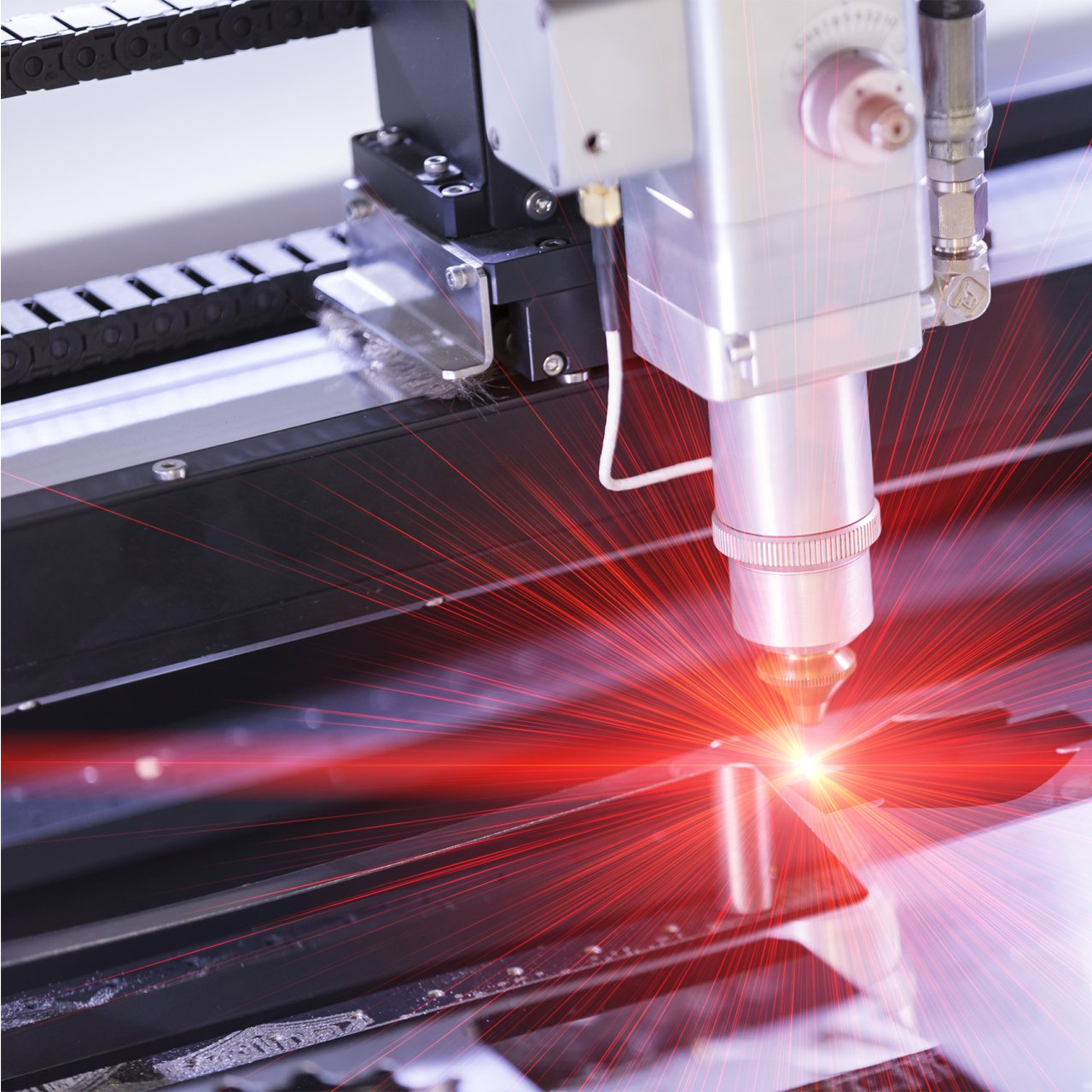 A machine is cutting a piece of metal with a red light coming out of it.
