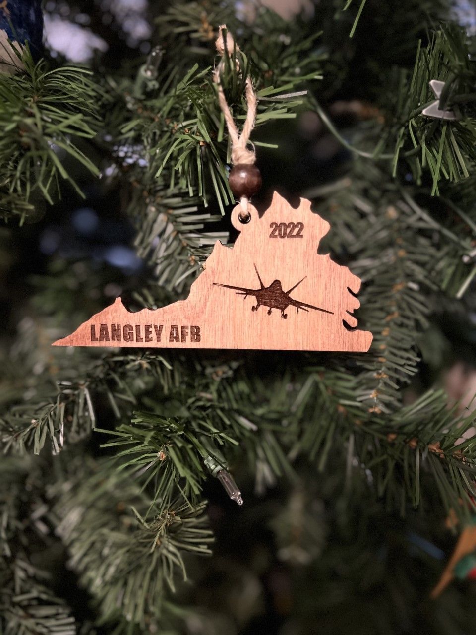 A wooden christmas ornament is hanging from a christmas tree.