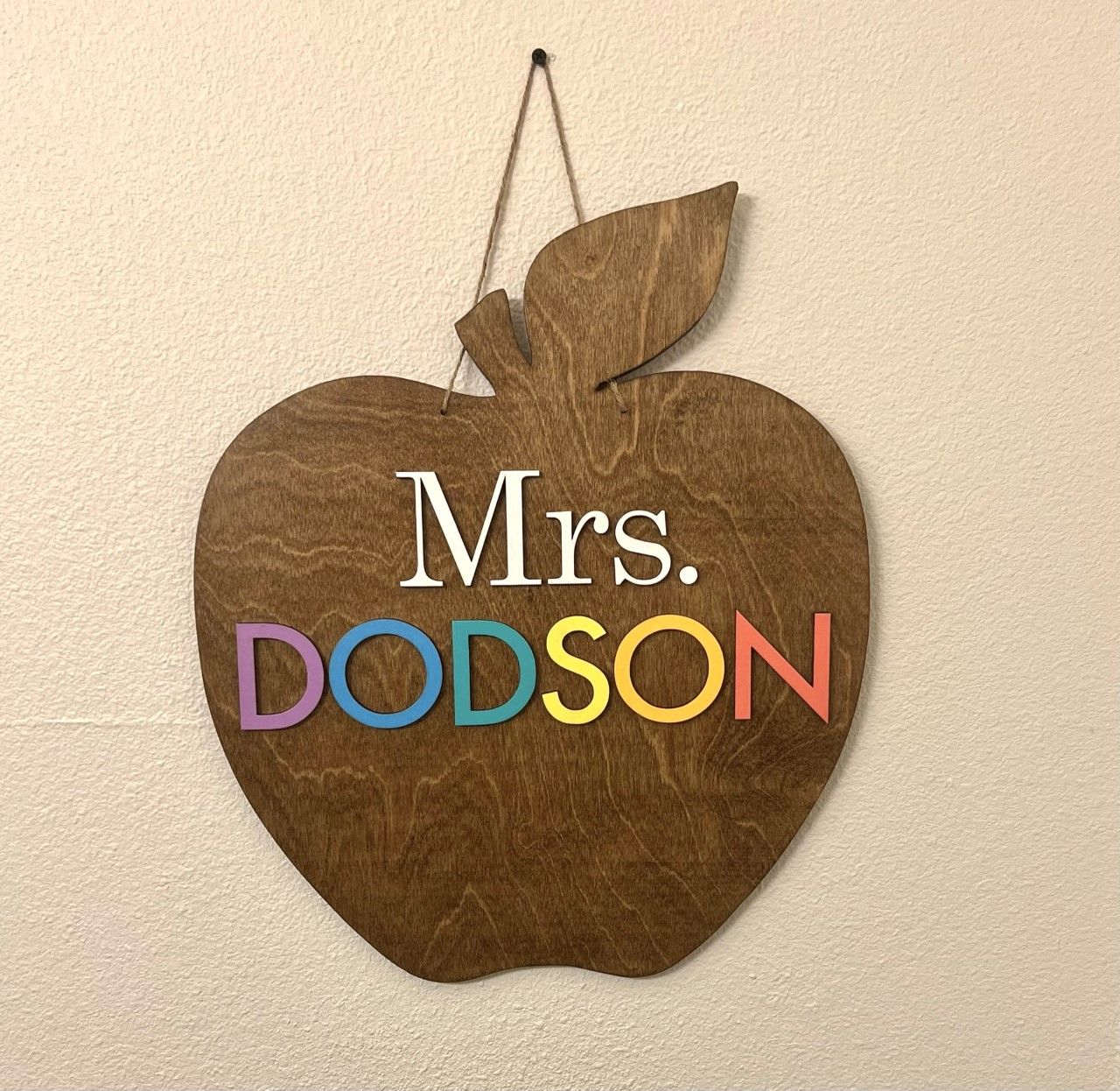 A wooden apple sign that says mrs. dodson is hanging on a wall.