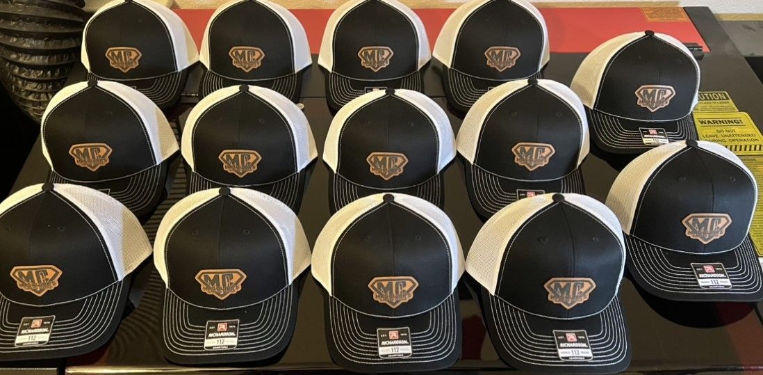 A bunch of black and white baseball caps are sitting on a table.