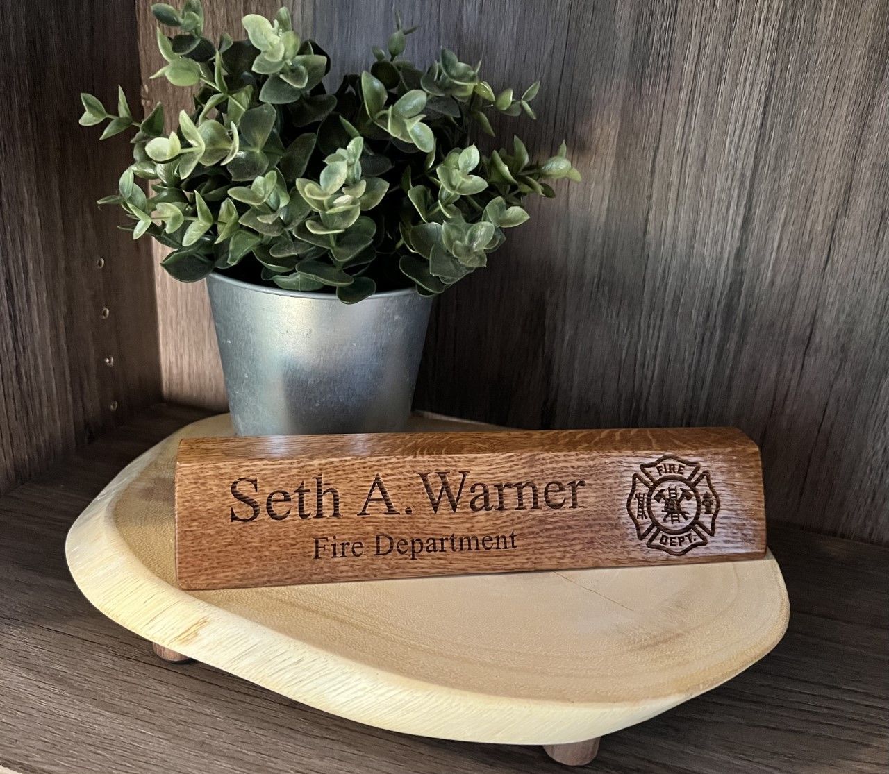 A wooden name plate for seth a. warner is sitting on a wooden tray next to a potted plant.