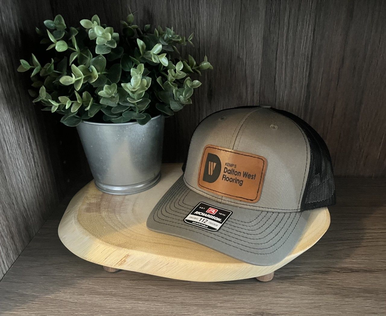 A hat is sitting on a wooden tray next to a potted plant.