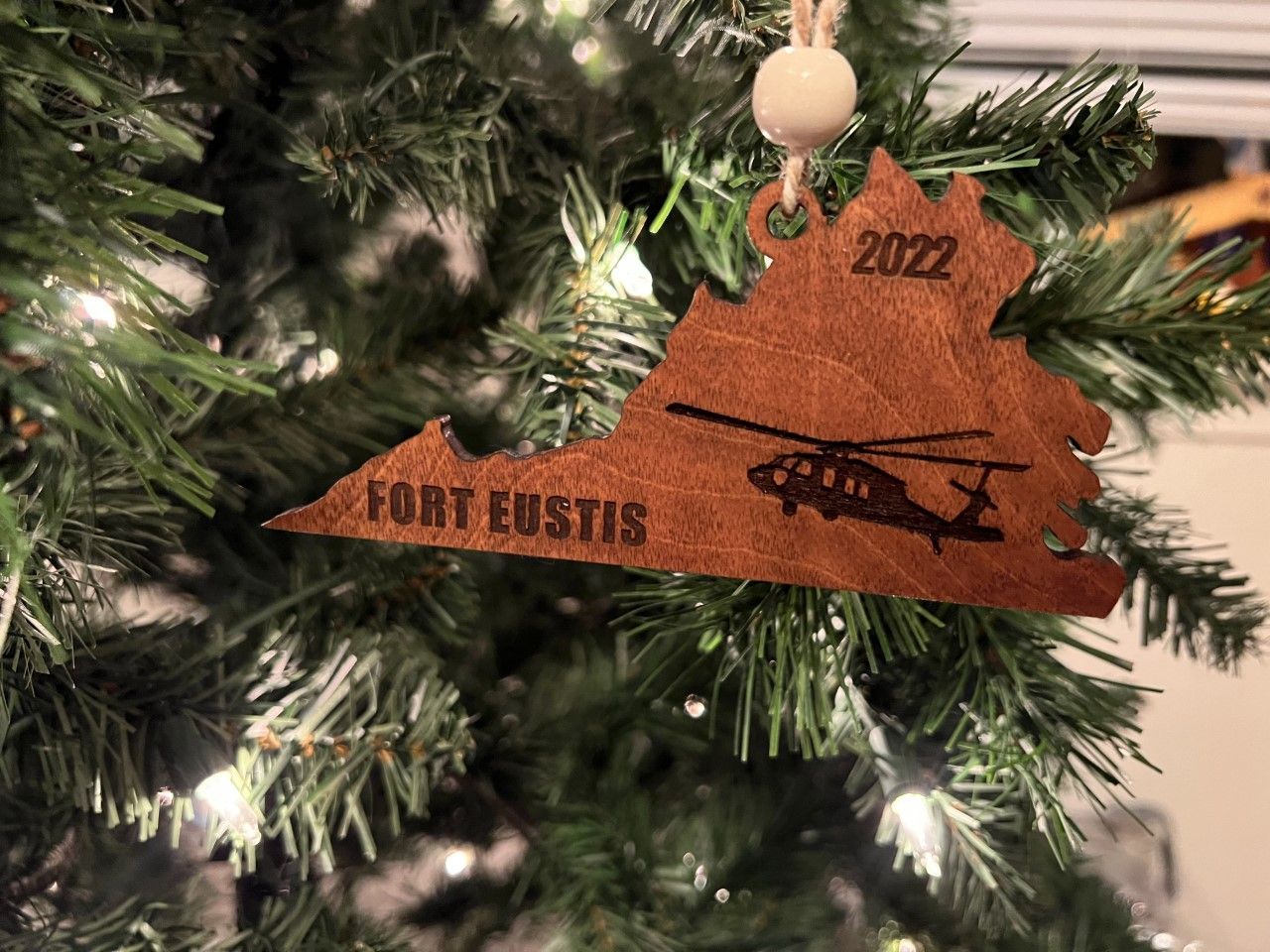 A christmas ornament with a helicopter on it is hanging on a christmas tree.