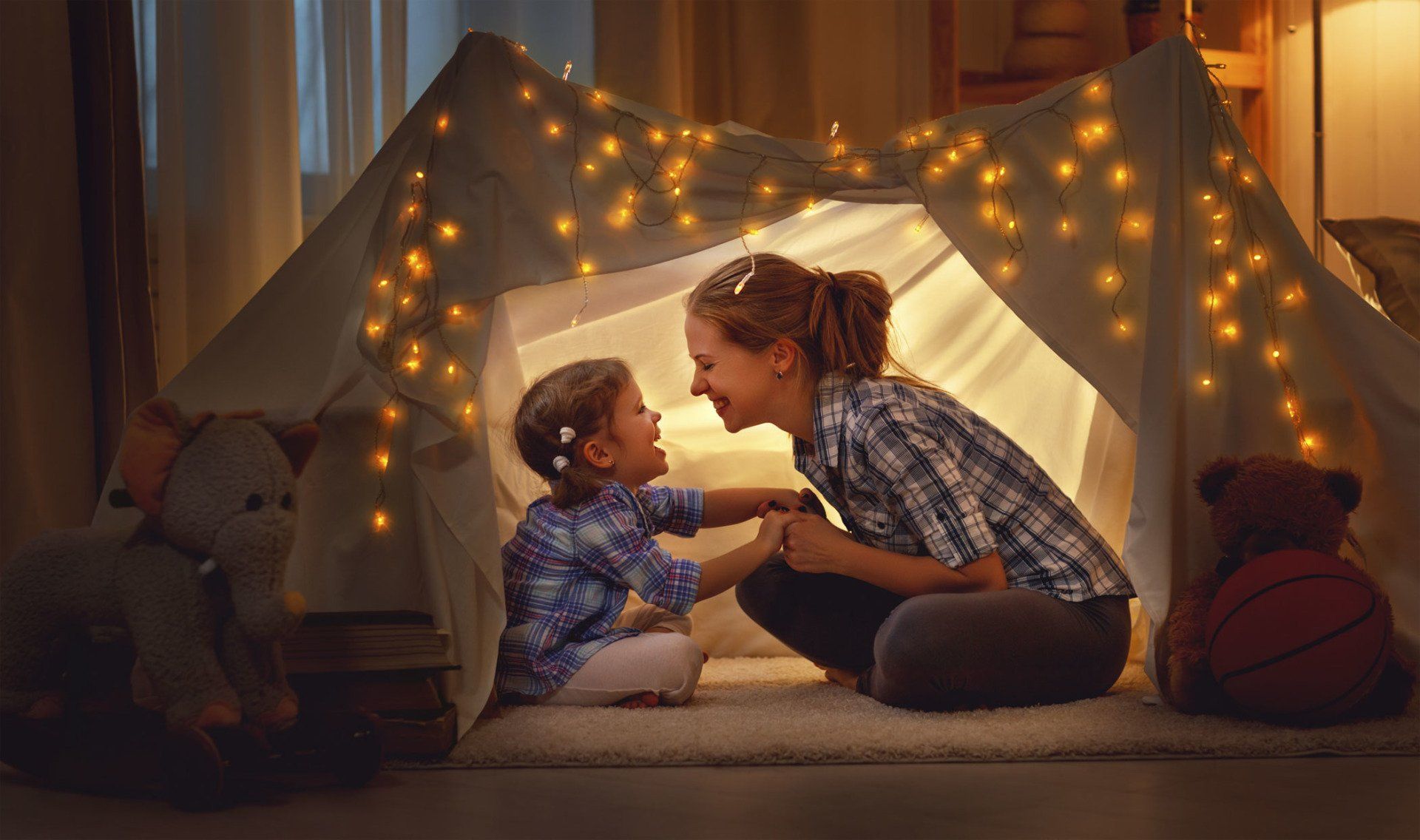 happy mother and daughter playing at home in tent
