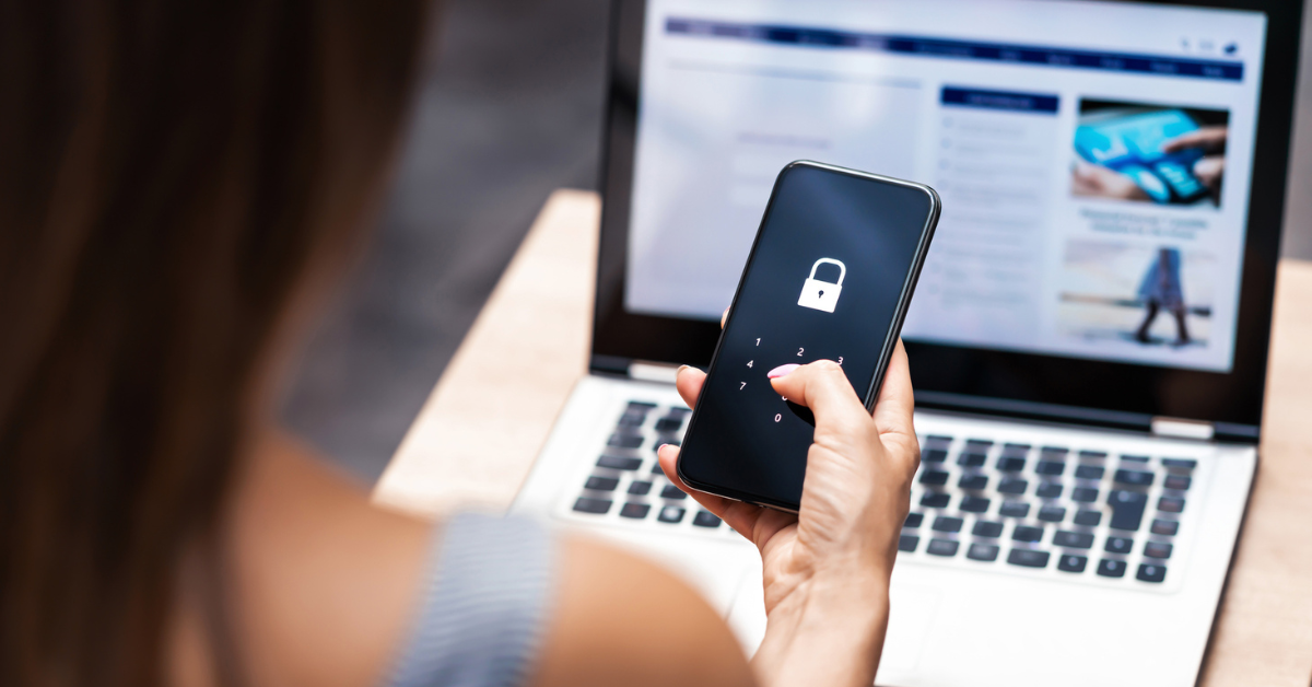 Person unlocks smartphone with laptop in background; security lock visible.