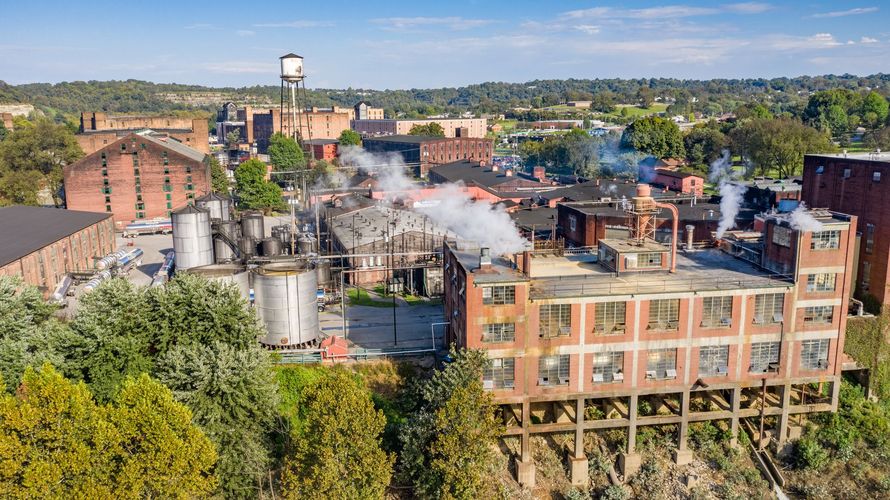 An aerial view of a factory with smoke coming out of the chimneys.