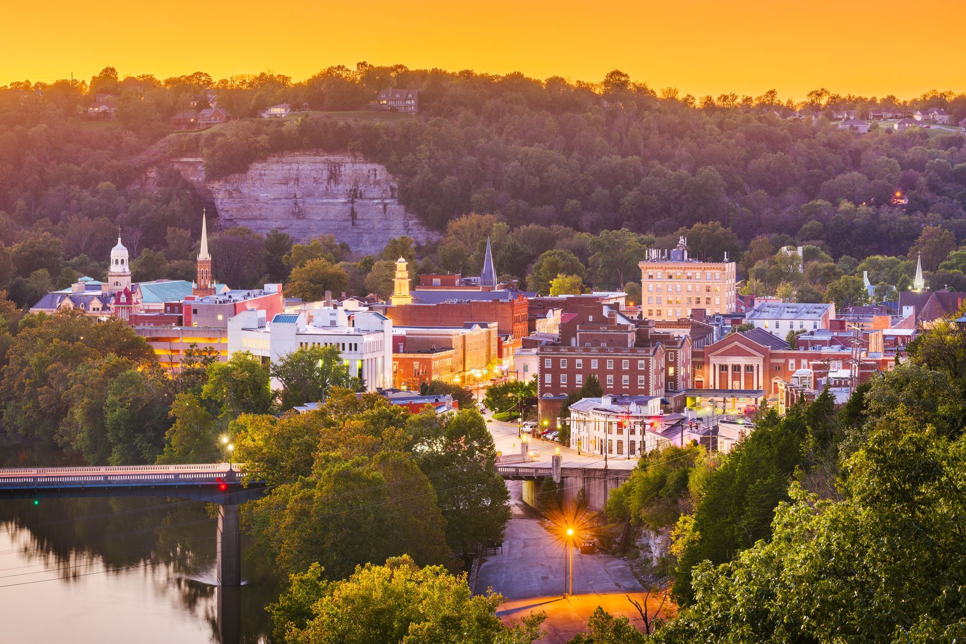 An aerial view of a small town next to a river at sunset.