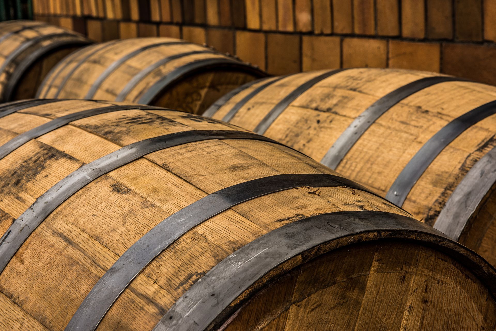 A row of wooden barrels stacked on top of each other in a warehouse.