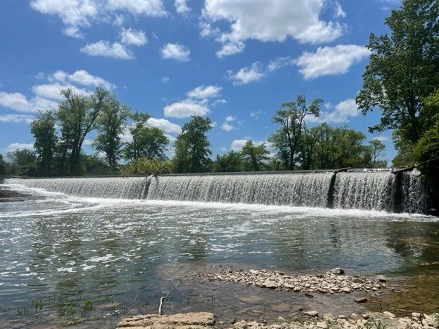 There is a waterfall in the middle of a river surrounded by trees.
