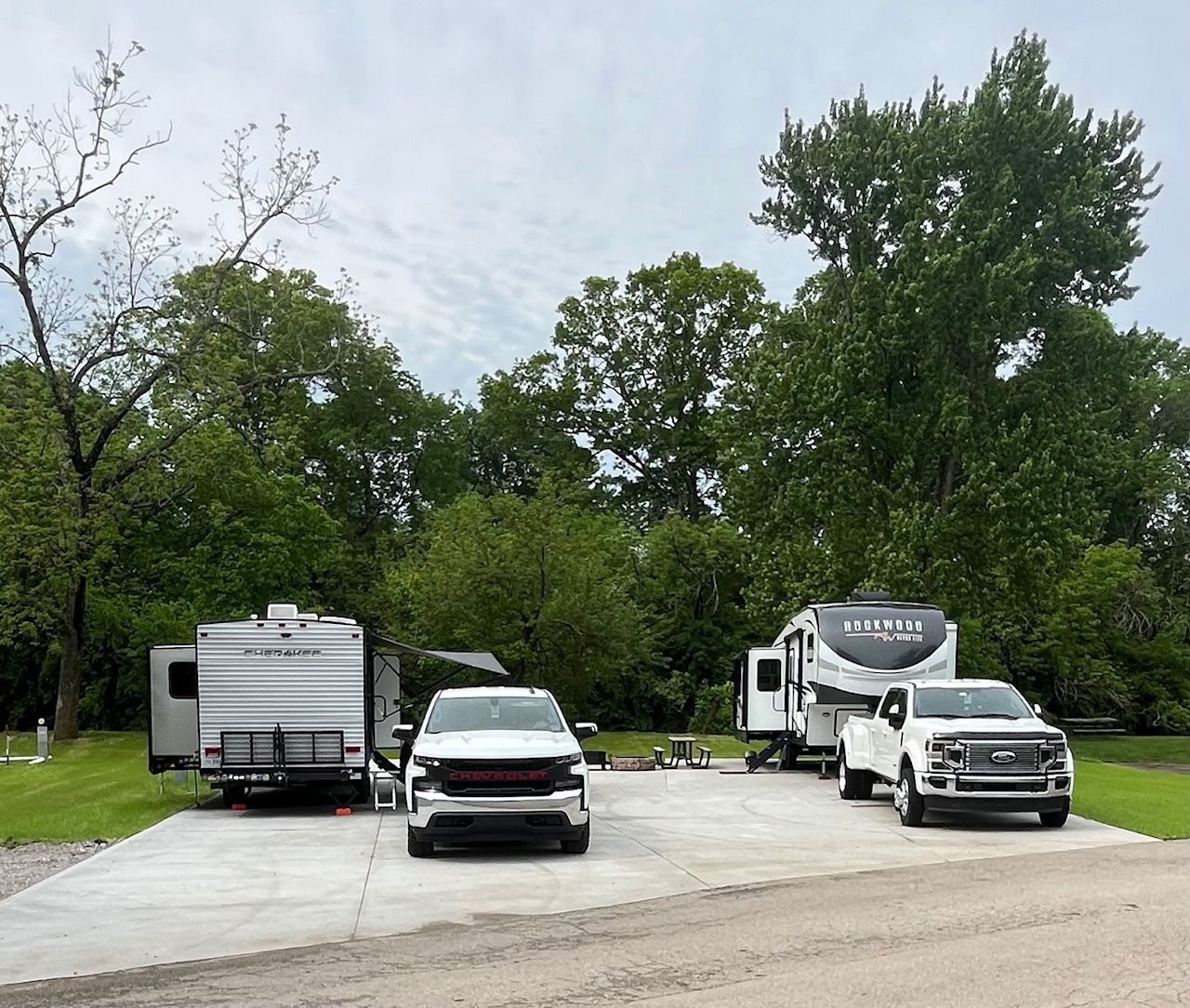 A couple of cars are parked in a driveway next to a rv.