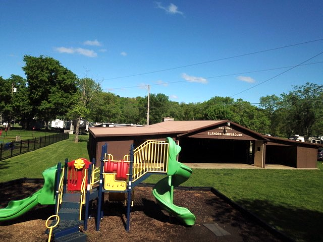 A playground with a green slide in front of a house