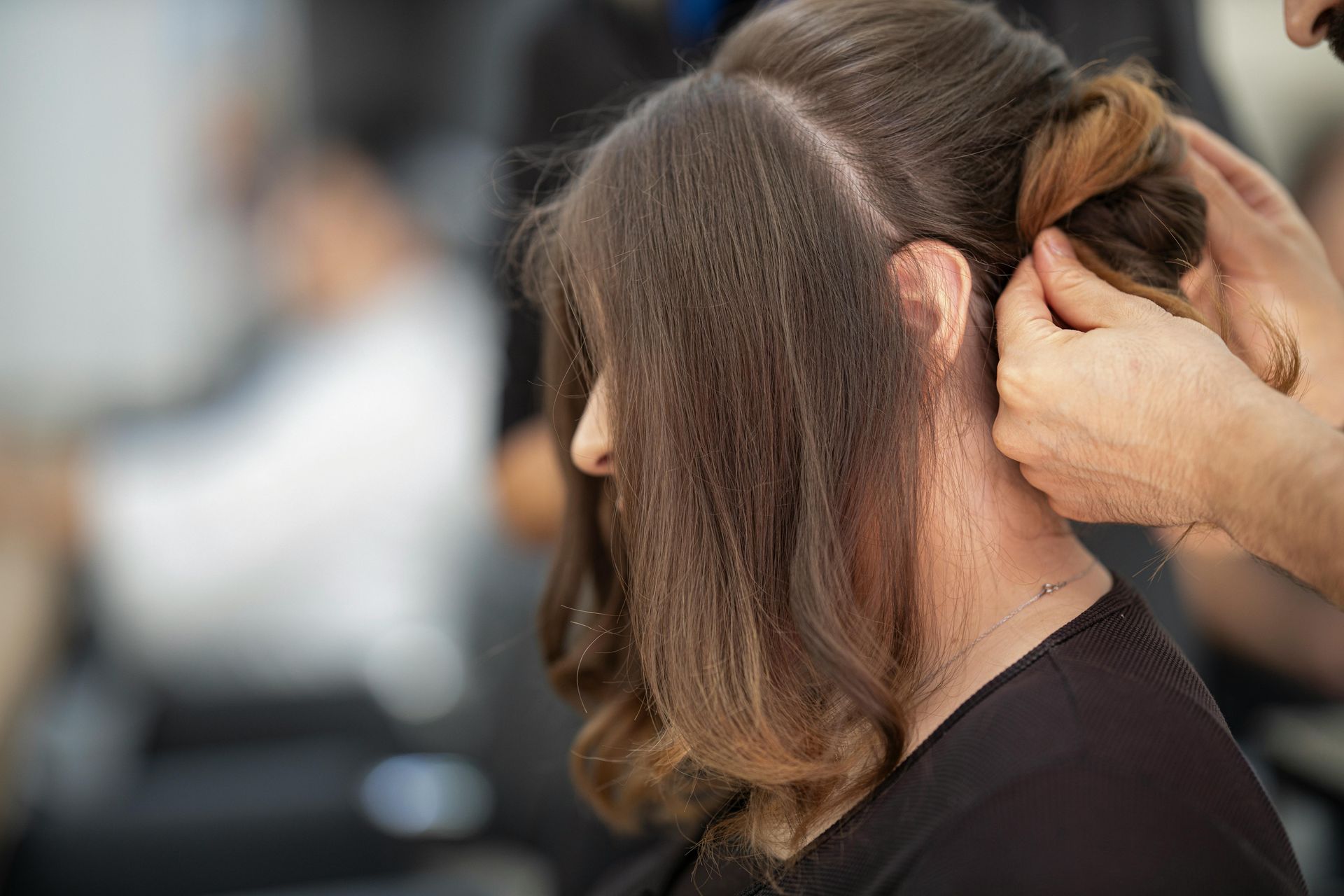 A woman is getting her hair done by a hairdresser in a salon.
