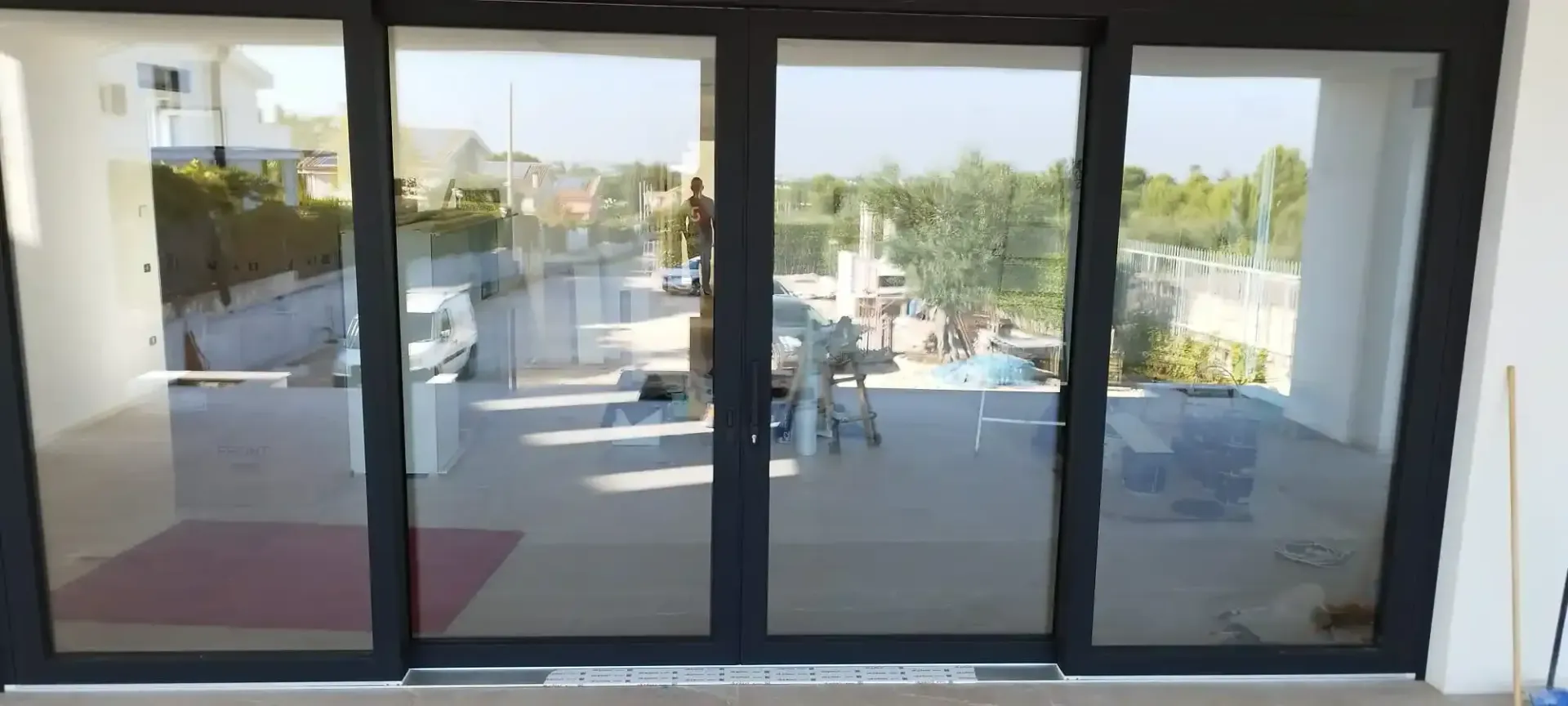 Porte scorrevoli in vetro che si affacciano su una strada del quartiere, viste dall'interno di un edificio.