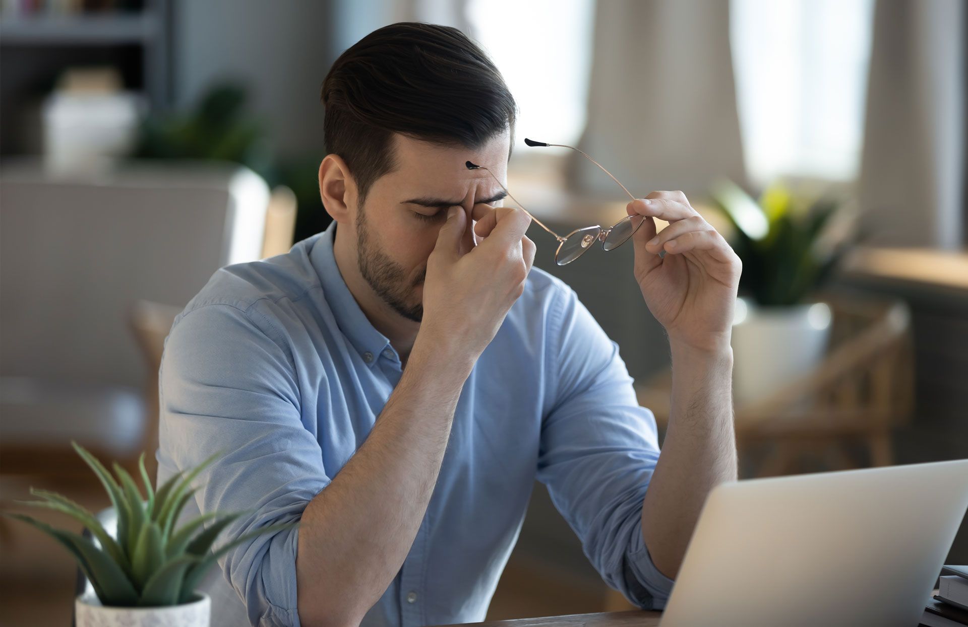 A man is sitting at a desk experiencing a migraine in Kennesaw.