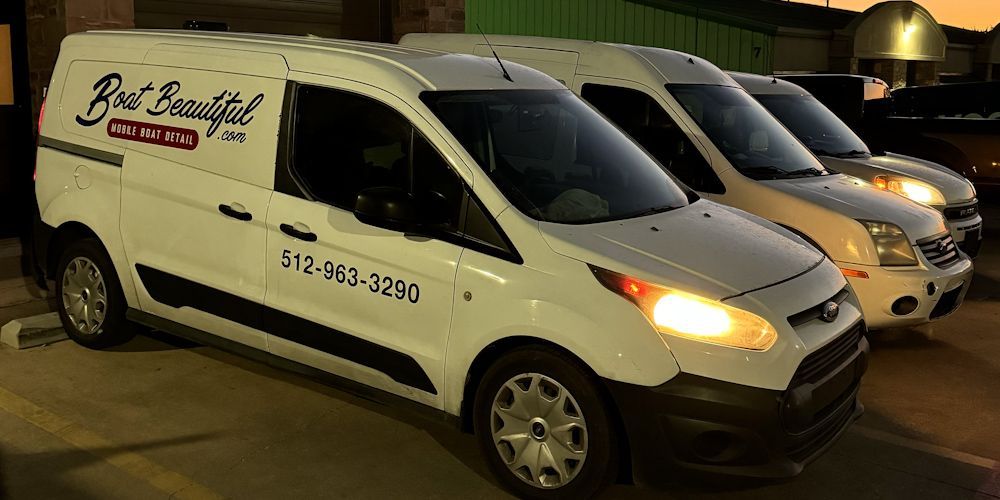 Three white vans are parked next to each other in a parking lot.