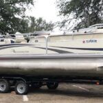A boat is being towed by a trailer in a parking lot.