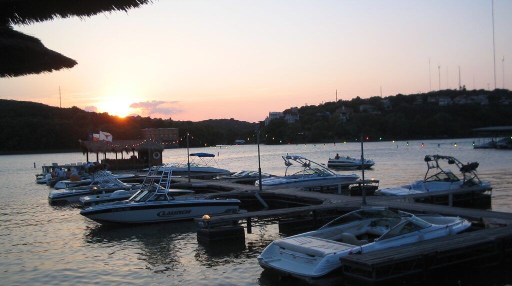 Several boats are docked at a marina at sunset