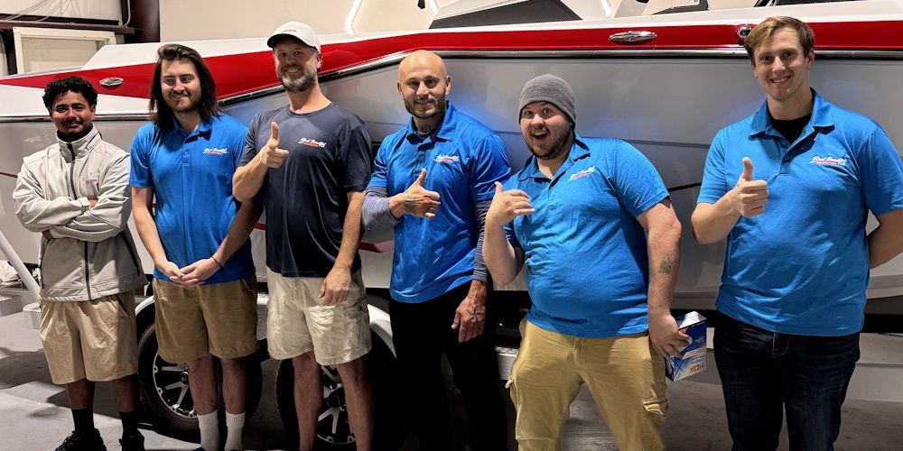 A group of men are posing for a picture in front of a boat.