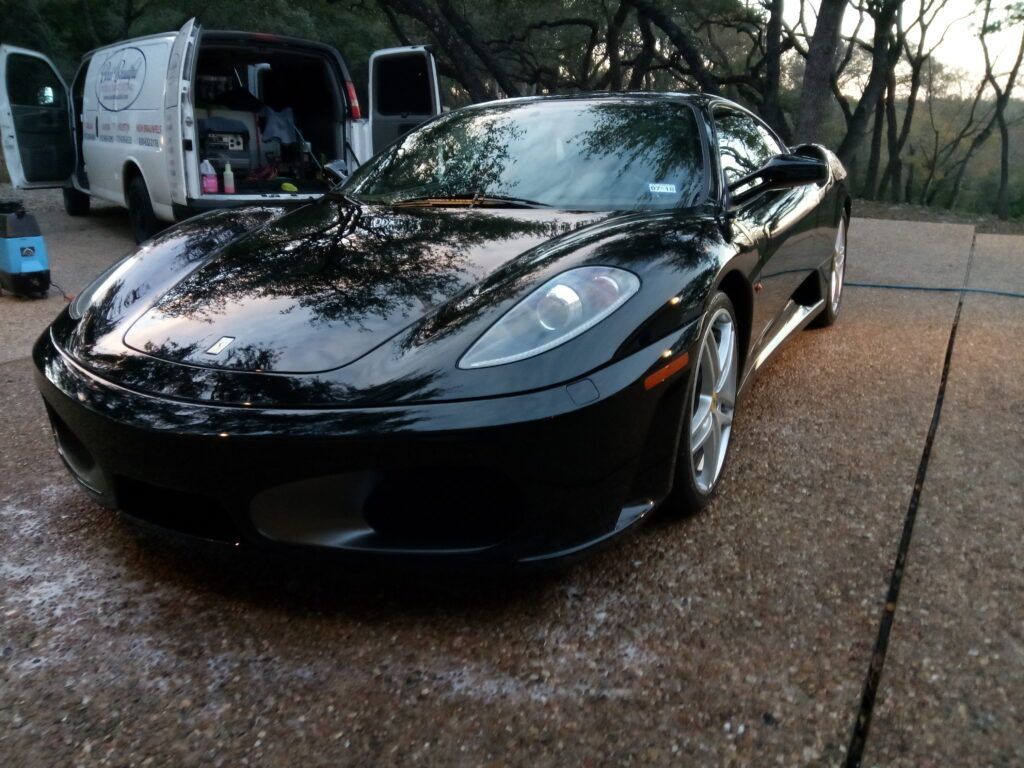 A black sports car is parked next to a white van