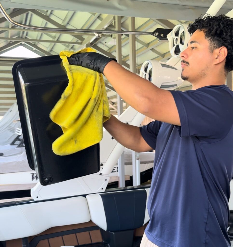 A man wearing black gloves is cleaning a boat with a yellow cloth