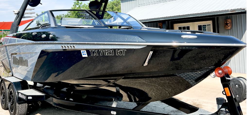 A black boat is parked on a trailer in front of a building.