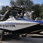 A blue and white boat is parked on a trailer.