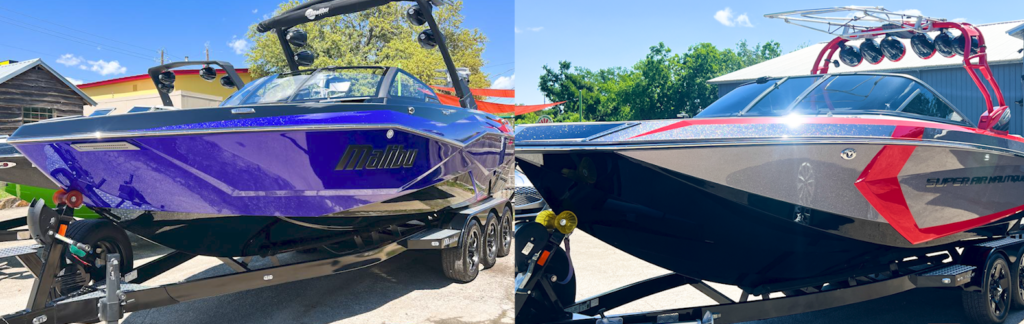 A purple boat is parked next to a black boat on a trailer.