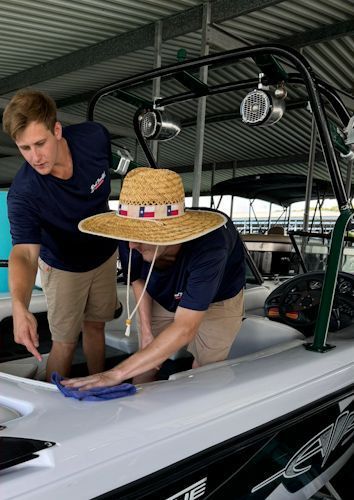 Two men are cleaning a boat with a straw hat on.