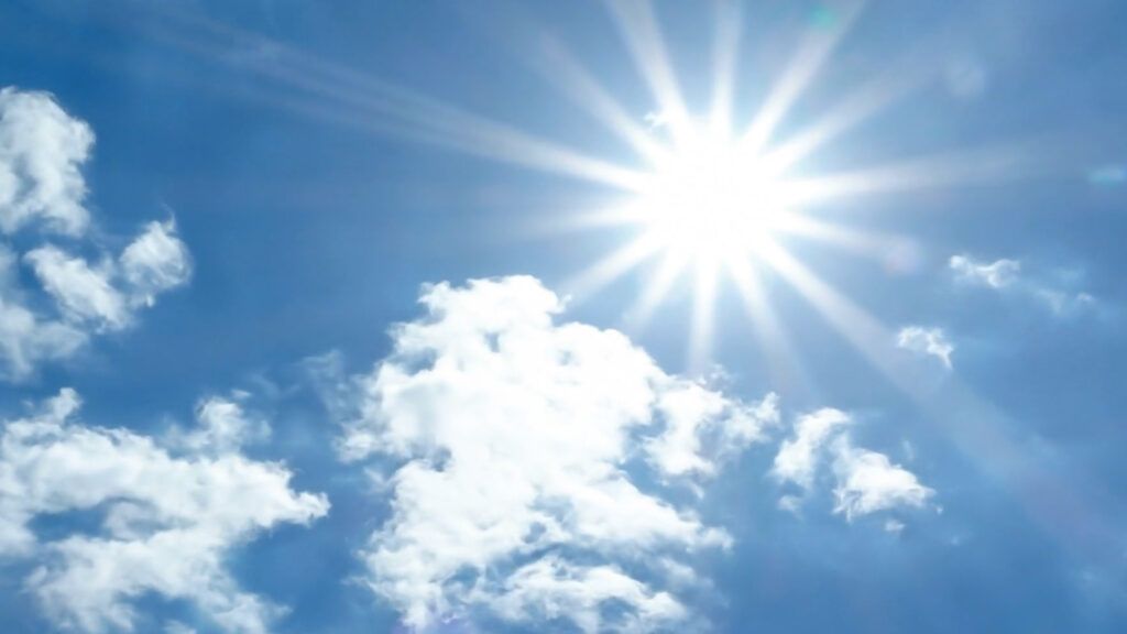 The sun is shining through the clouds in a blue sky.