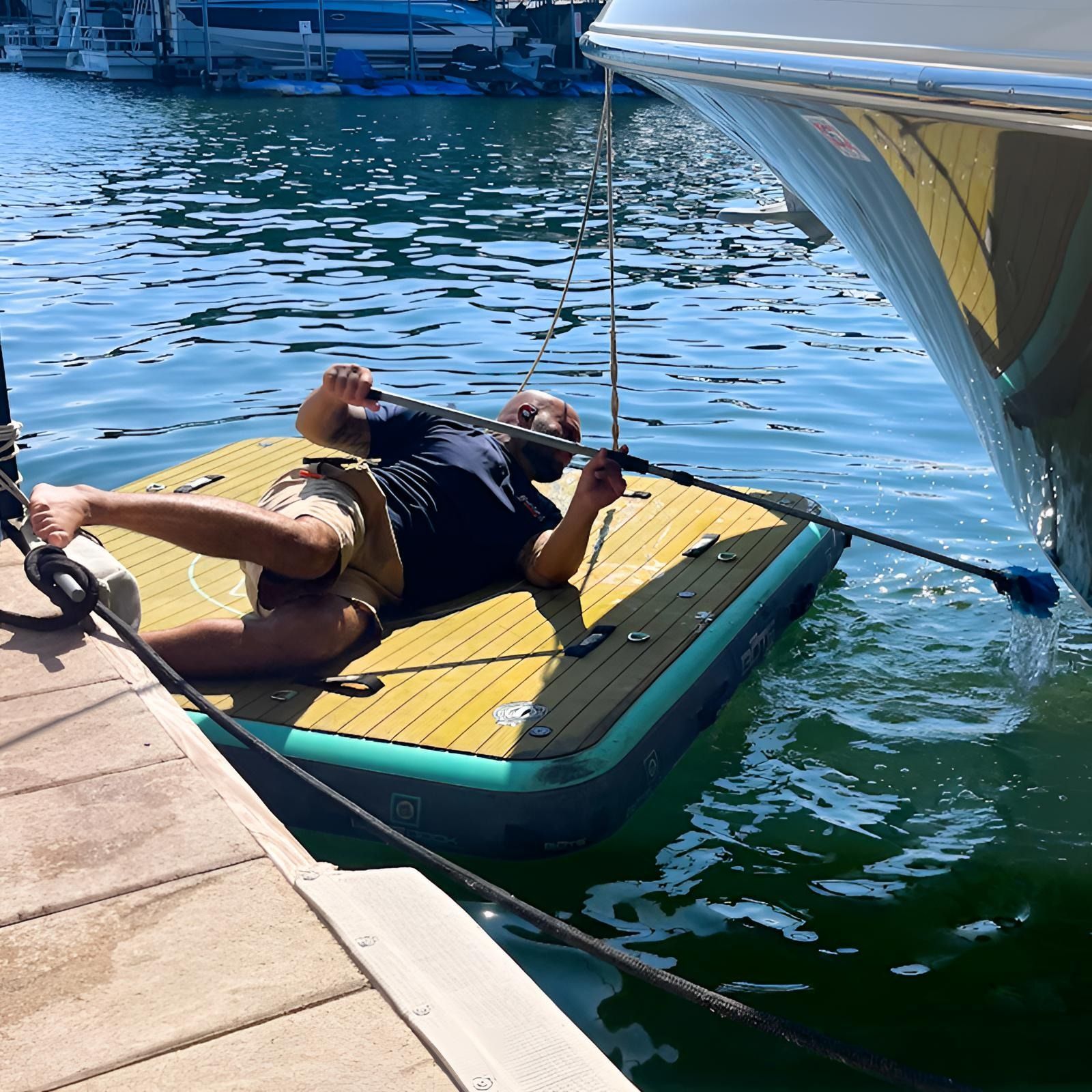 A man is laying on a raft in the water next to a boat