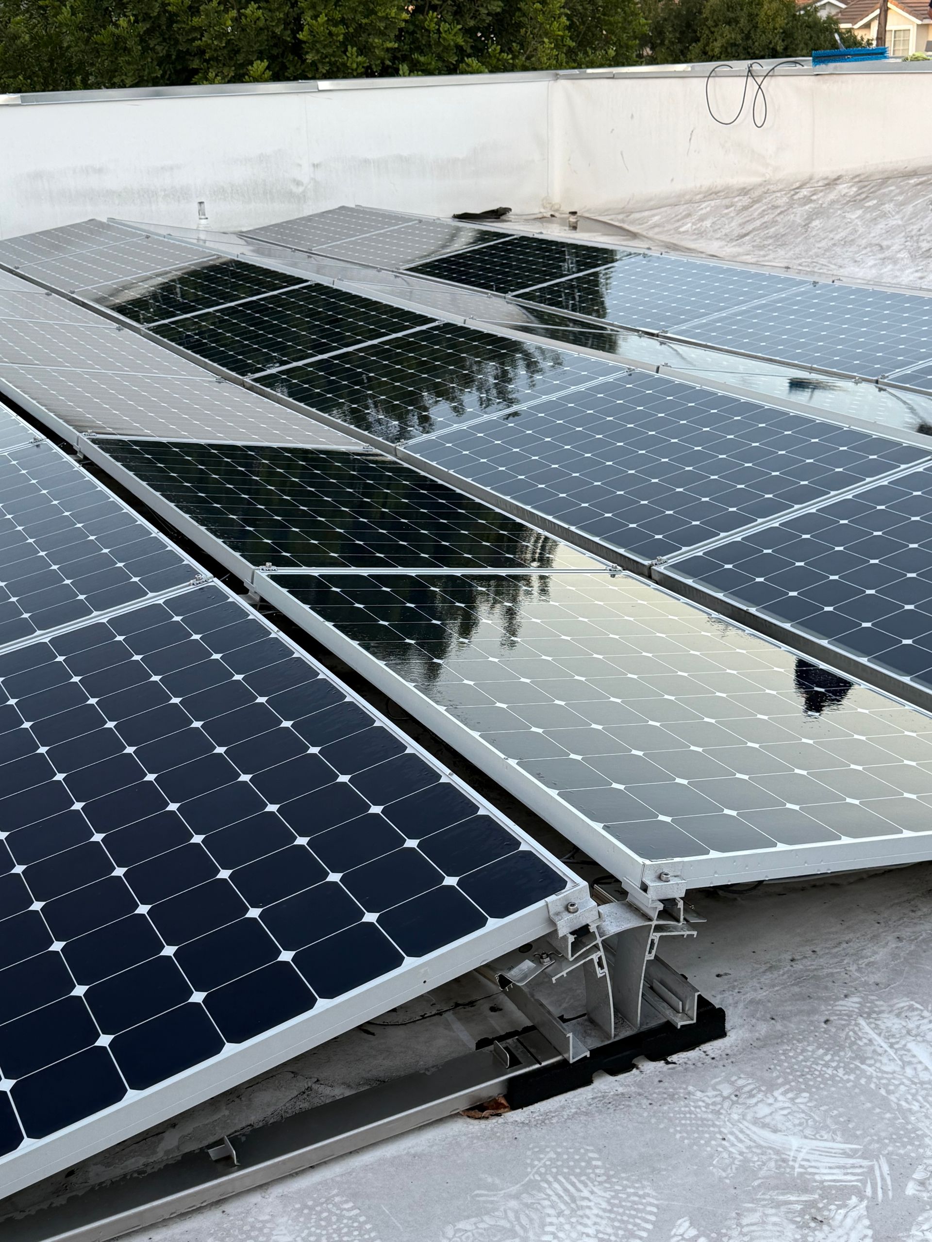 Solar panels installed on a flat rooftop, angled towards the sky. The panels are black and shiny.