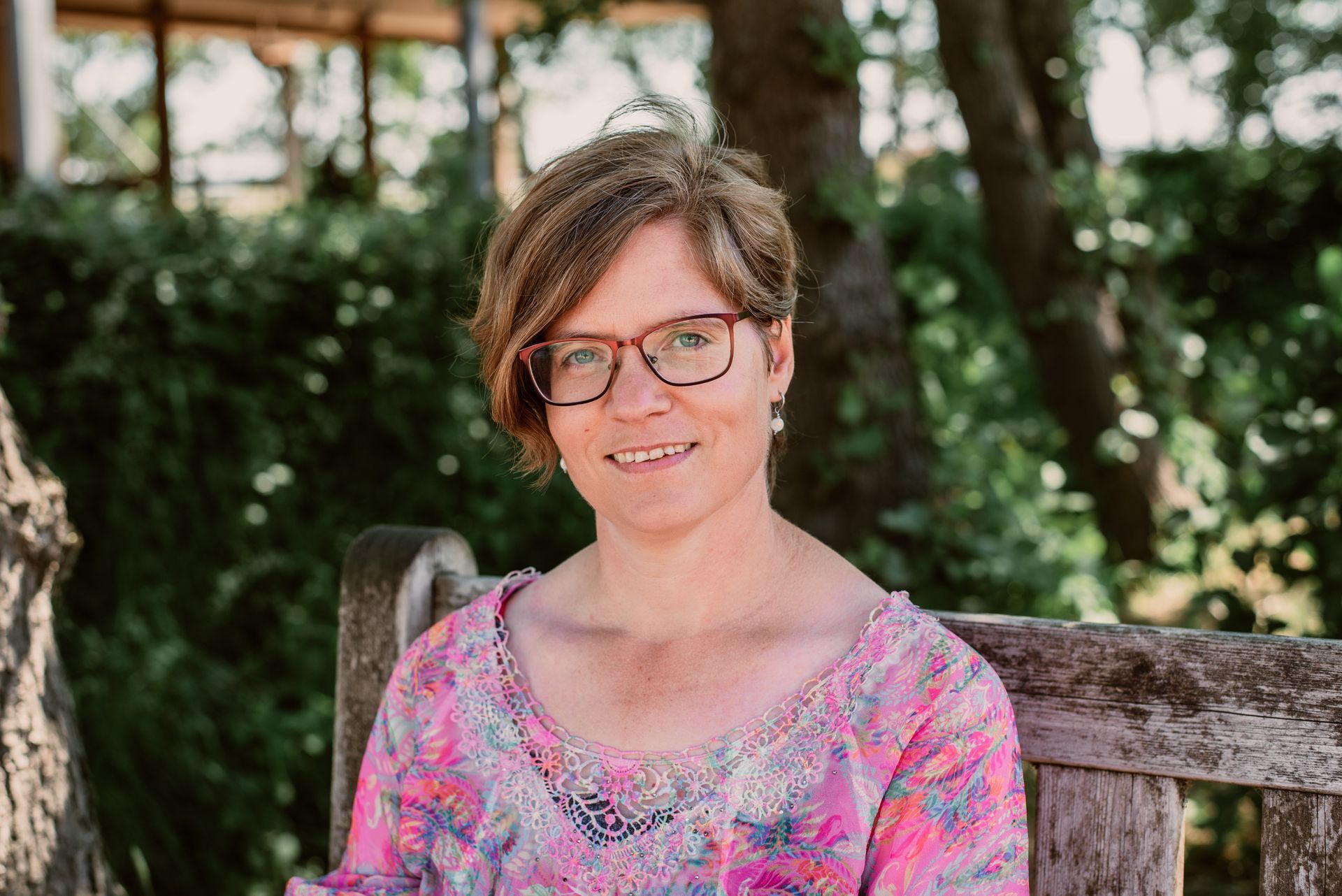 een vrouw met een bril en een shirt met luipaardprint lacht naar de camera