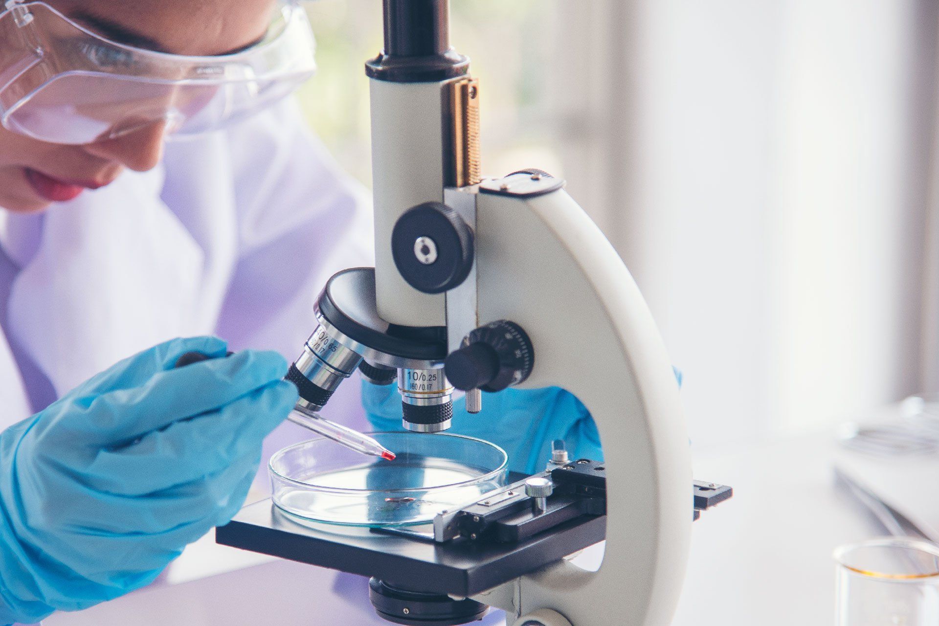 Un científico está mirando a través de un microscopio en un laboratorio.