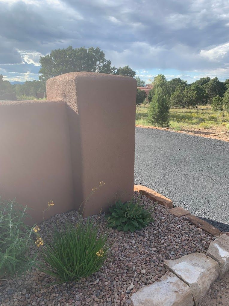 A brick wall is sitting next to a gravel road.
