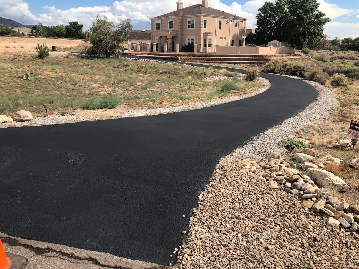 A large house is in the background of a curvy road.