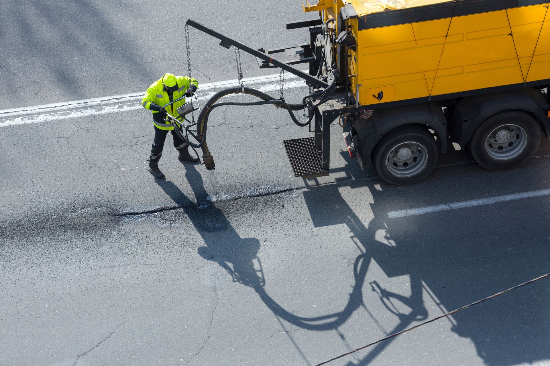 A man is standing next to a yellow truck on a street.