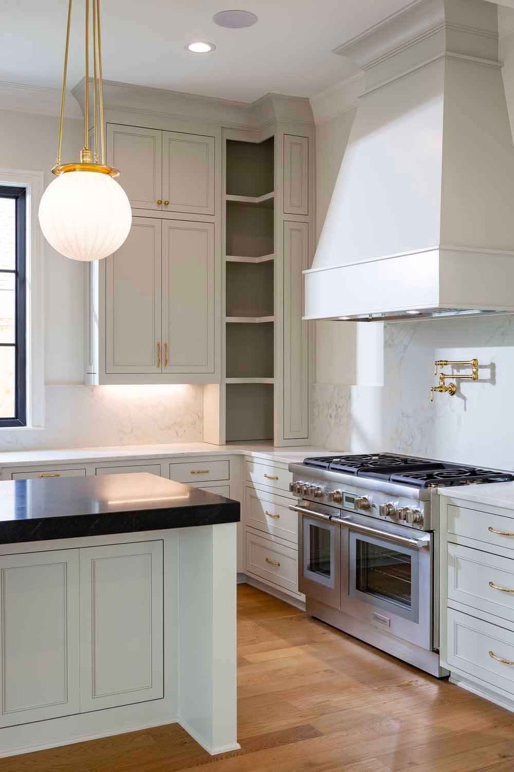 A bright, modern kitchen featuring white cabinets, a large stainless steel range, and a globe-style pendant light.